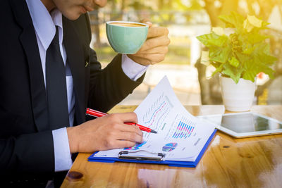 Midsection of man holding coffee cup on table