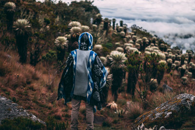 Rear view of man standing on field against plants