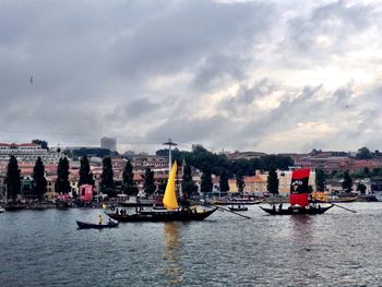 Boats in sea against cloudy sky