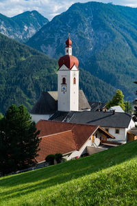 Built structure by trees and buildings against mountains