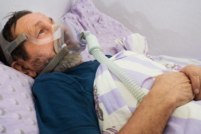 Male patient with oxygen mask lying on bed