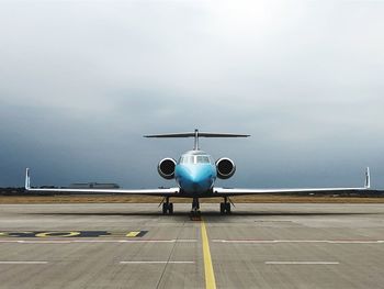 Airplane on airport runway against sky