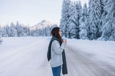 Rear view of woman standing on snow covered field