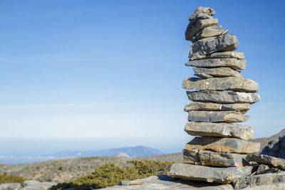 Stack of stones on rock against sky