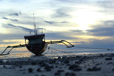 Nautical vessel on snow covered land against sky during sunset