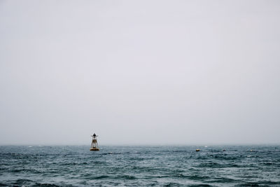 Sailboat in sea against clear sky