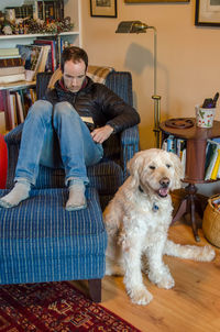 Man reading a book with a labradoodle