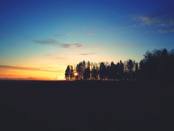 Silhouette trees on landscape against sky at sunset