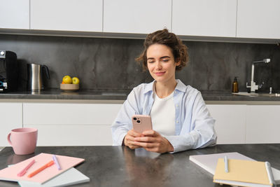 Young woman using mobile phone on table