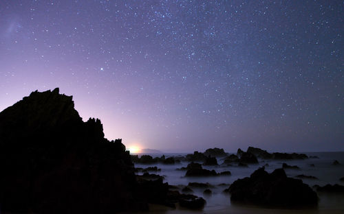 Scenic view of silhouette rocks against sky at night