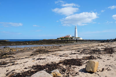 Lighthouse on beach against sky