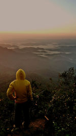 Rear view of man standing on landscape against sky