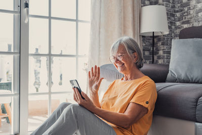 Young man using mobile phone while sitting on sofa at home