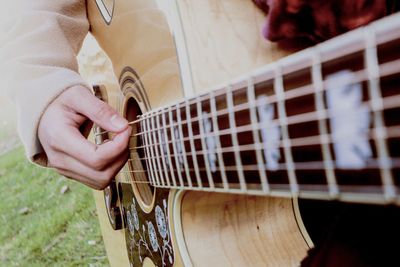 Midsection of person playing guitar on field