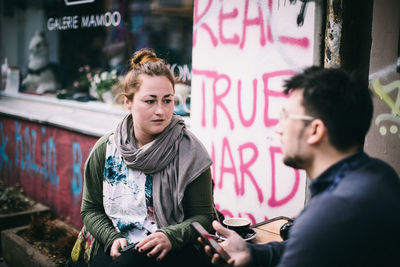 Young woman looking away while sitting on text