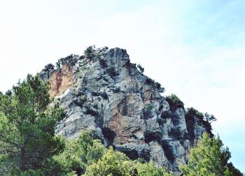 Low angle view of rocks on cliff against sky