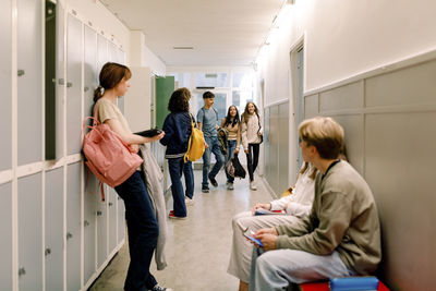 Teenage girls and boys in illuminated school corridor