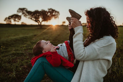 Mother and daughter playing on field during sunset