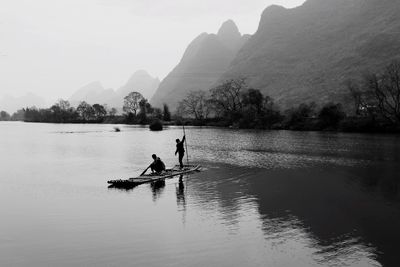 People in boat on river against sky