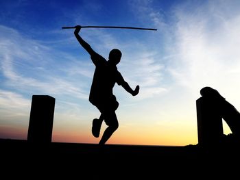 Silhouette people playing against sky during sunset