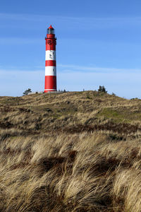 Lighthouse on field against sky