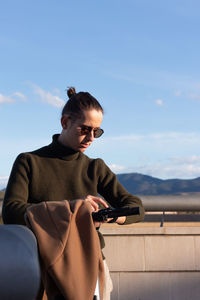 Portrait of young handsome man communicatin with his smart watch over a voice call under blue sky