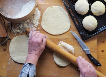 A woman rolls out the dough and forms buns for baking in a home 