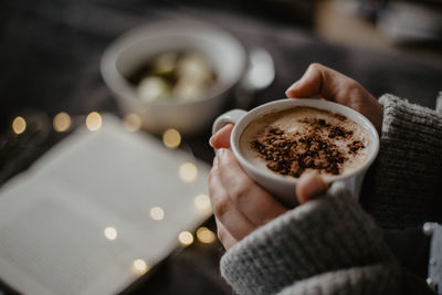 Cropped hand of person holding coffee on table
