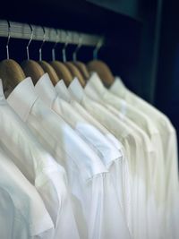 Close-up of white shirts hanging in closet