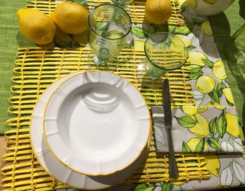 High angle view of bowl with dinking glasses and lemons on table