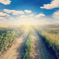 Road amidst field against sky