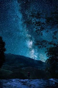 Man standing on field against stars in sky at night