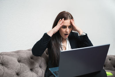 Young man using mobile phone while sitting on wall