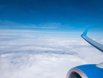 Airplane flying over cloudscape against blue sky