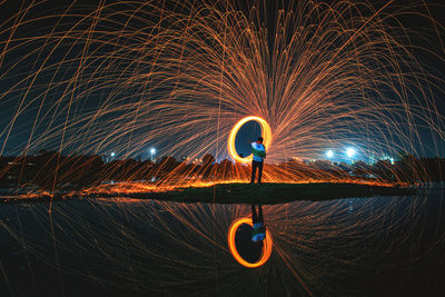 Full length of man with illuminated lights against sky at night