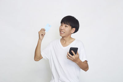 Young man using mobile phone against white background