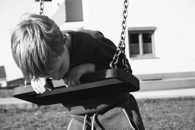 Boy leaning on swing at playground