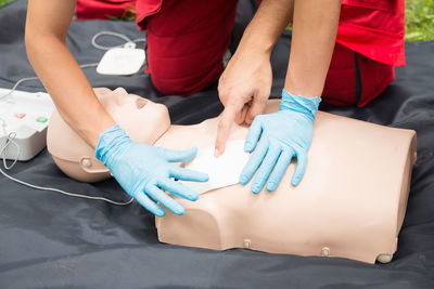 Cropped hand of man instructing while paramedic practicing cpr on dummy