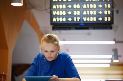 Close-up of young woman with digital tablet sitting in airport