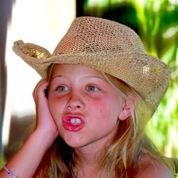 Cheeky girl making funny face and  wearing a straw hat 