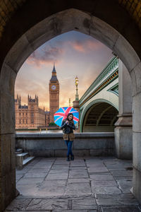 Woman standing against big ben seen through archway