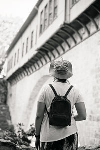 Rear view of woman wearing hat standing against building