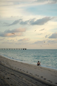 Man at beach against sky during sunset