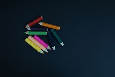 High angle view of colored pencils on table against black background
