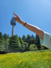 Low section of man holding plant against clear sky