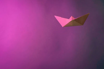 Close-up of paper boat against pink background