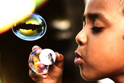 Close-up side view of girl blowing bubble