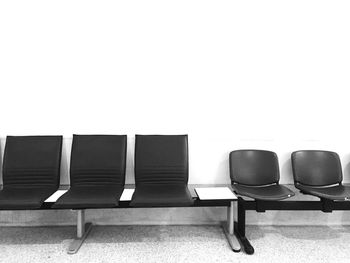 Empty chairs in row against wall