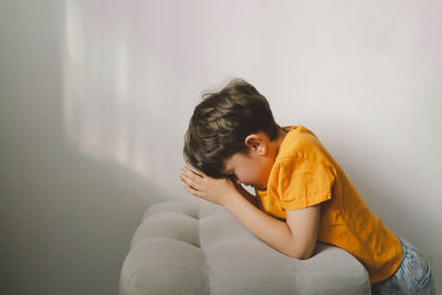 A boy in an orange t-shirt prays at home. concept for faith