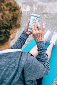 Woman using mobile phone while sitting on footpath